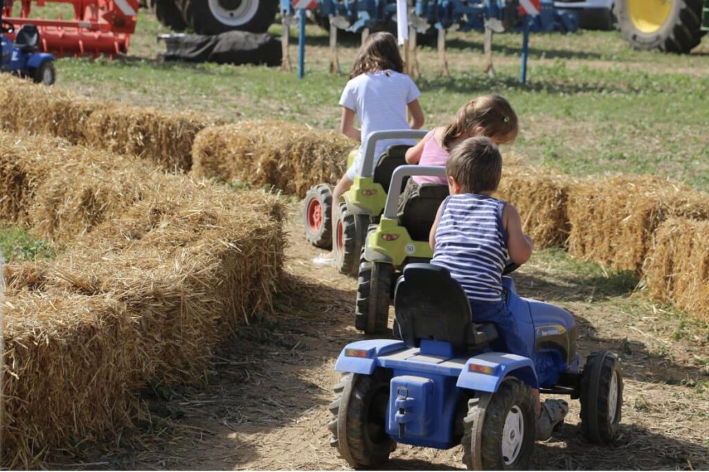 Enfants sur mini-tracteur à pédales lors du Festival de la Terre.